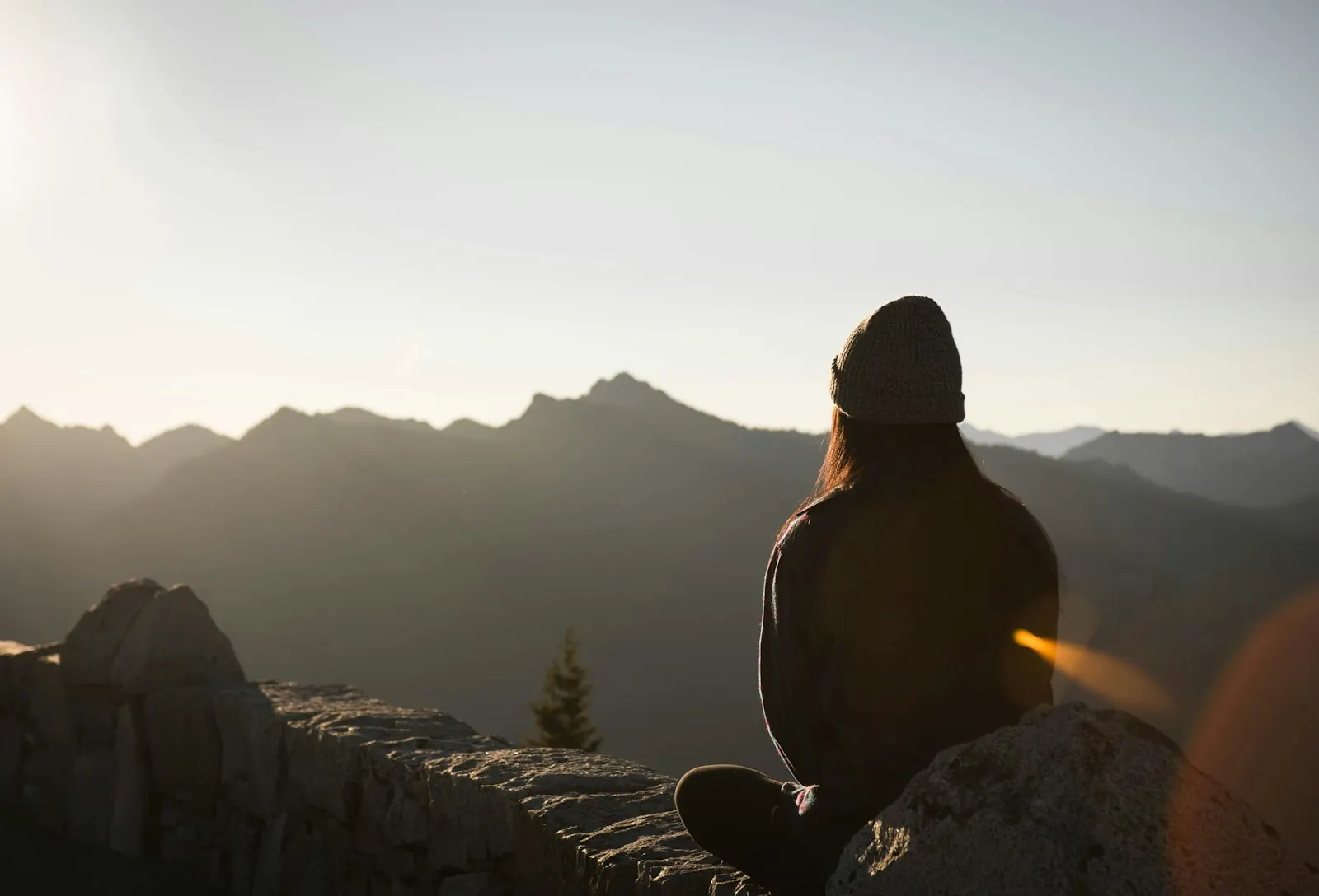 Person sitting quietly at a mountain overlook in warm evening light
