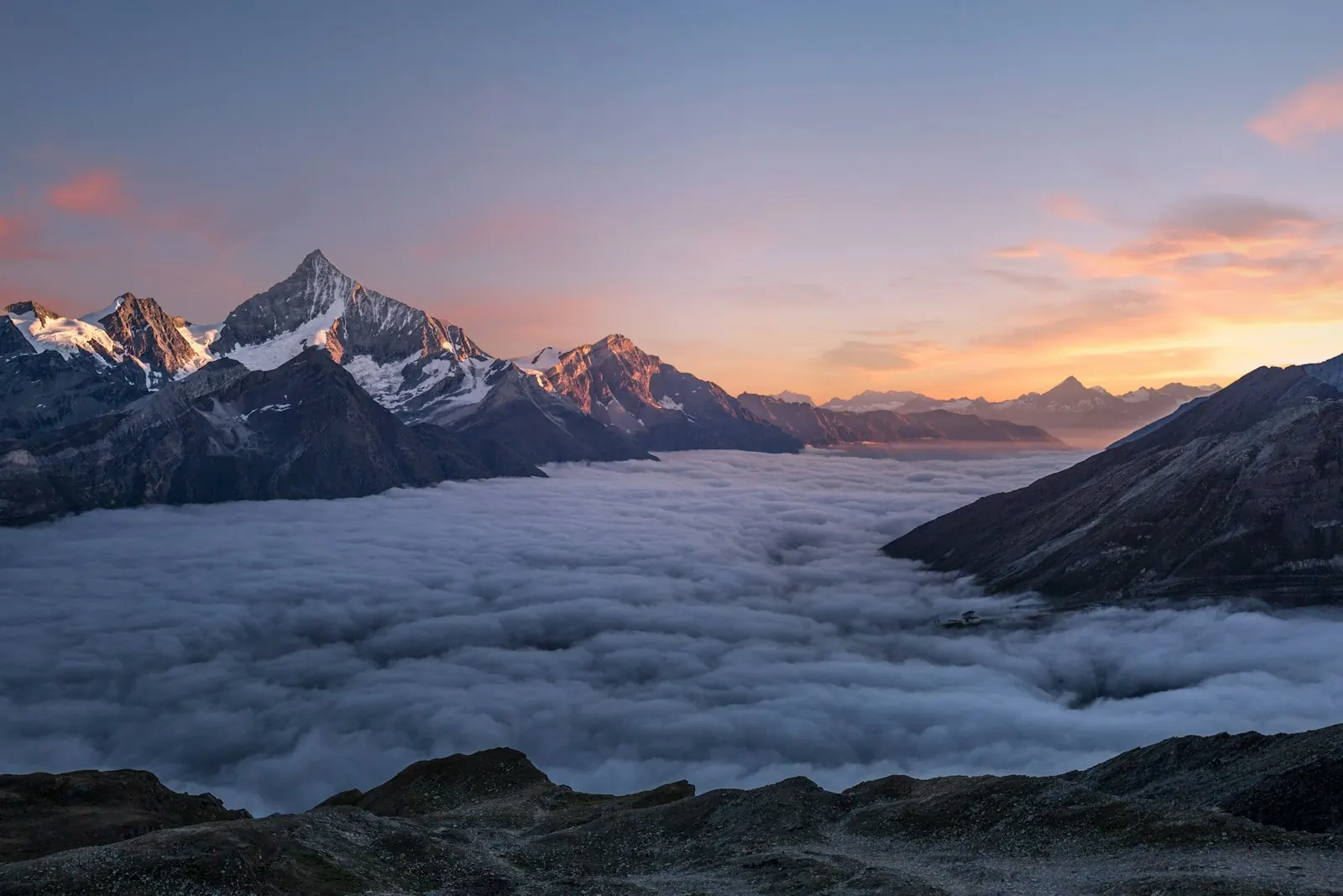 Alpine ridgeline at dusk above a sea of clouds — light and shadow in balance
